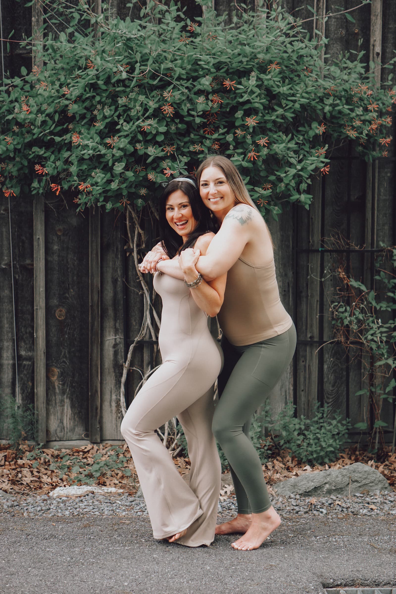 Sarah and Erin standing together outdoors under flowering greenery.